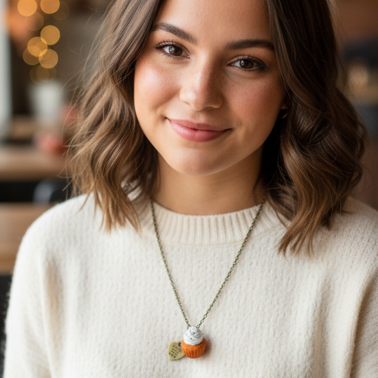 Amy wearing a white sweater and necklace with a blurred indoor background