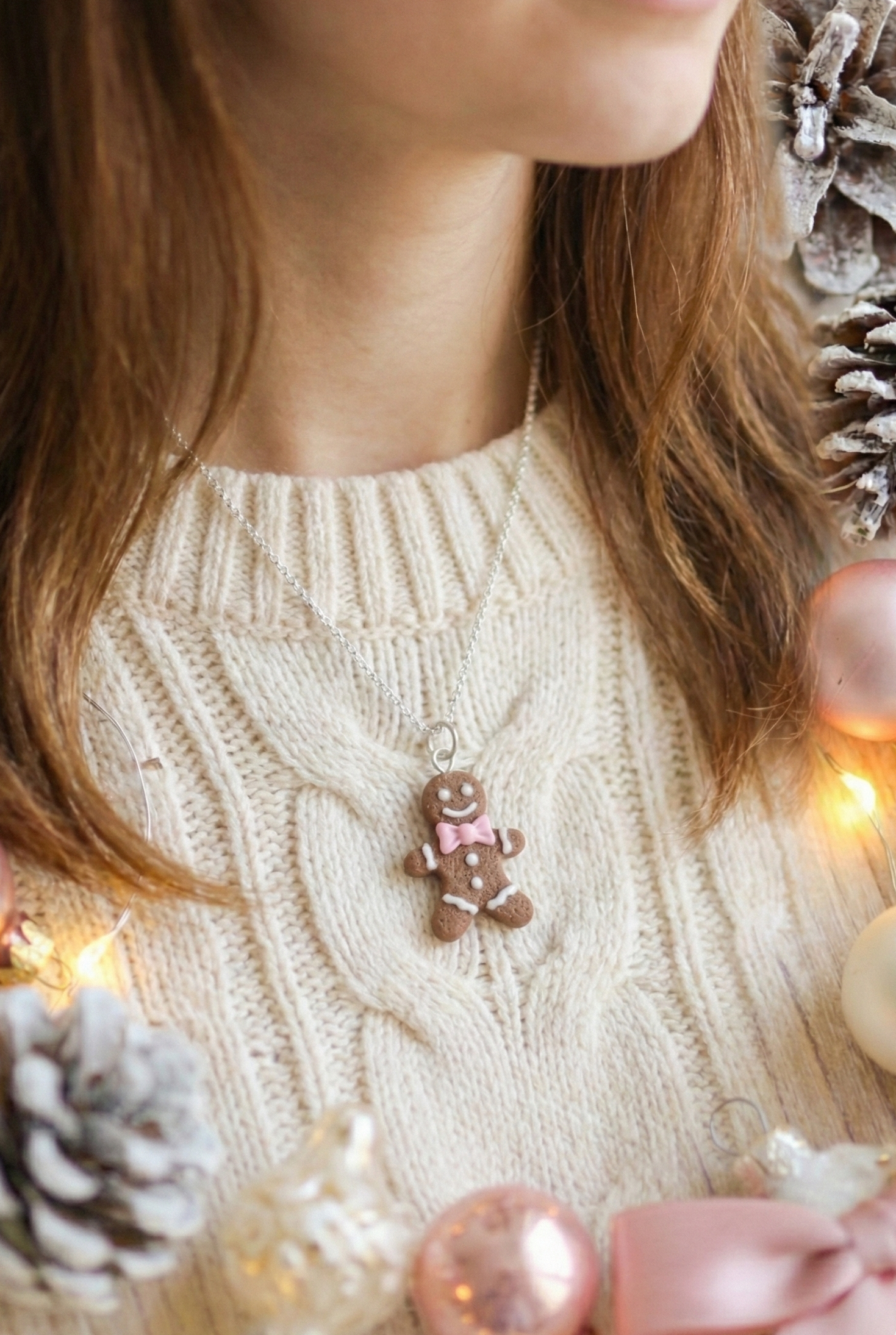 Person wearing a beige sweater with a gingerbread man ornament, surrounded by Christmas decorations.