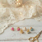 Set of small earrings on a wooden surface with lace fabric and decorative lights in the background.