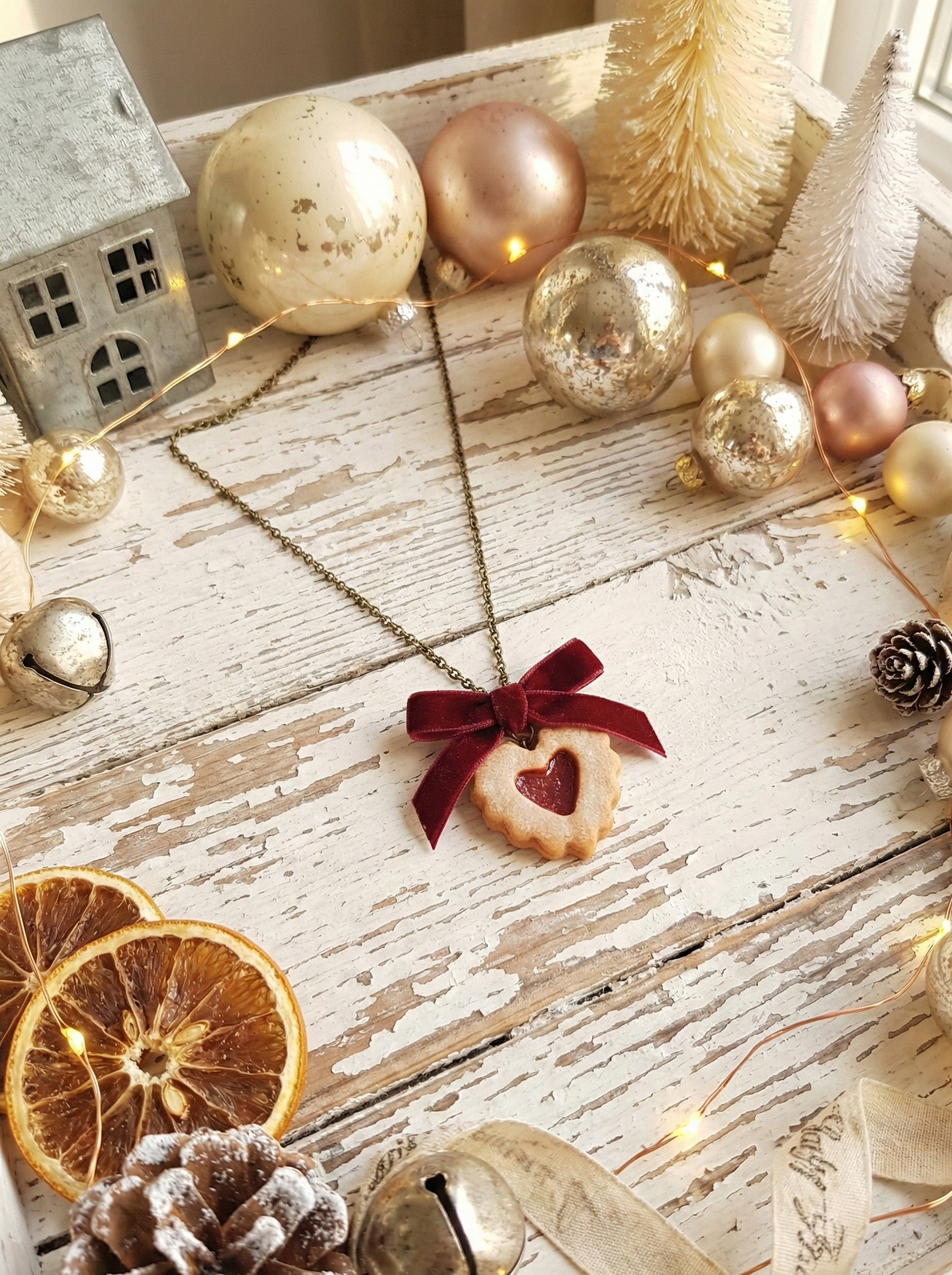 Polymer clay Linzer Cookie Necklace with a heart pendant on a wooden surface with Christmas decorations