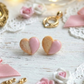 Heart-shaped cookies with pink and gold accents on a decorative surface with flowers and ribbons.
