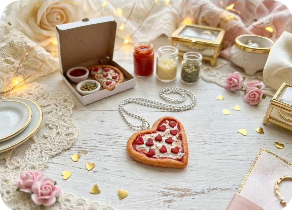 Heart-shaped pizza with jewelry on a decorative table setting with candles and flowers.
