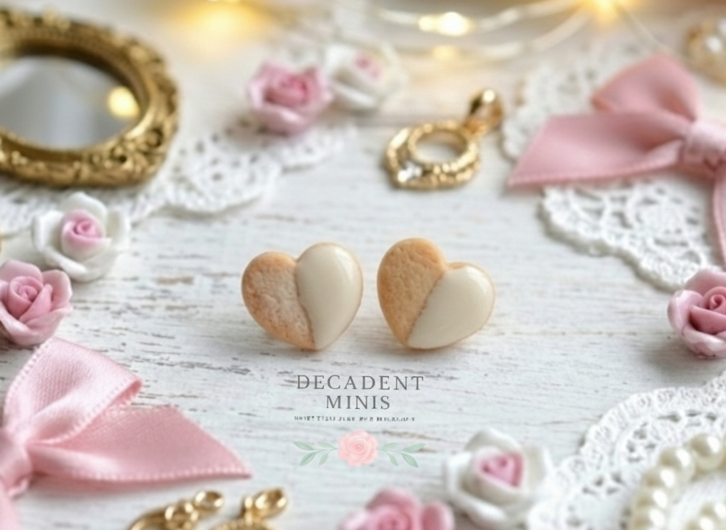 Heart-shaped cookie earrings on a decorative surface with flowers and ribbons.