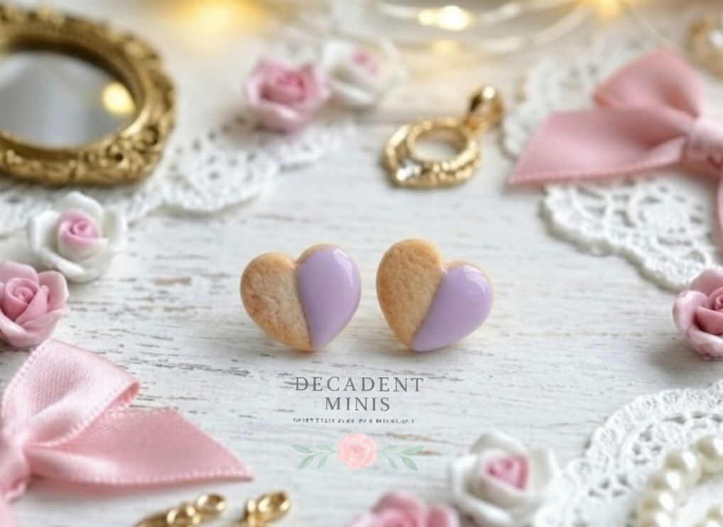 Heart-shaped cookies with lavender icing on a decorative surface with bows and frames.