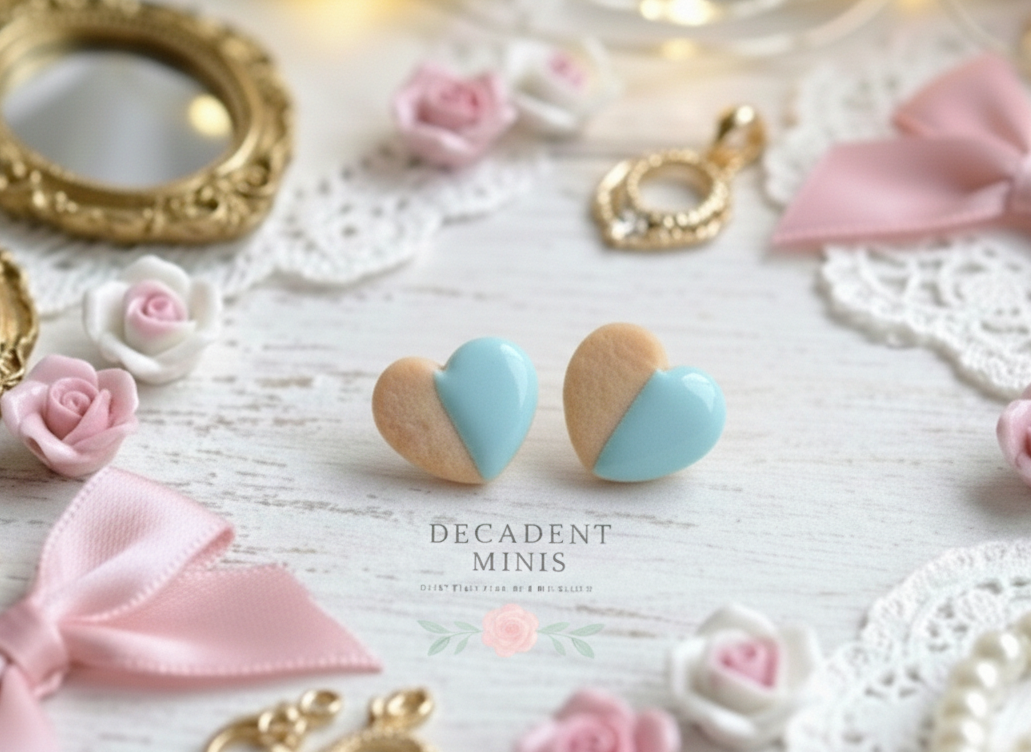 Heart-shaped cookie earrings with pastel colors on a decorative background with bows and roses.
