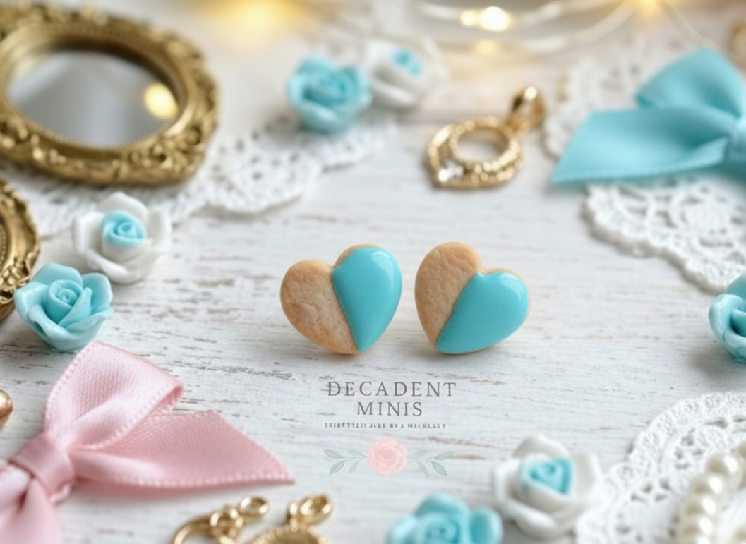 Heart-shaped cookie earrings with tiffany blue frosting design on a decorative background with bows and flowers.