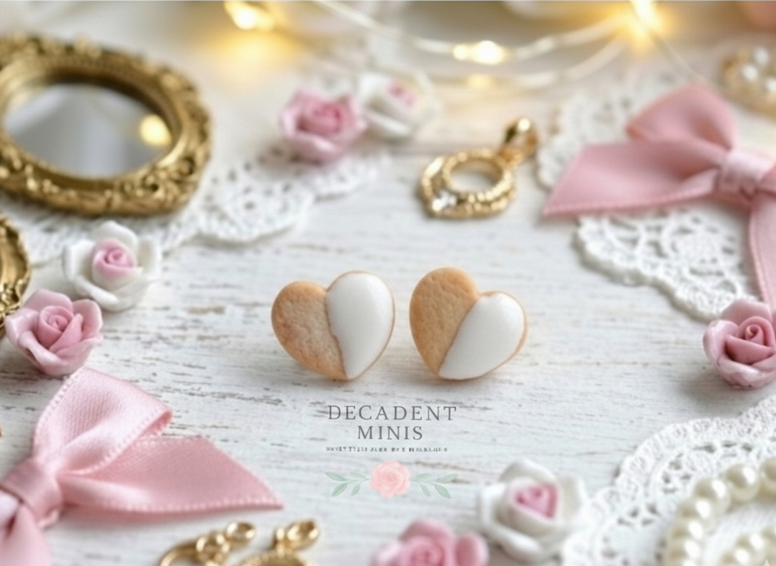 Heart-shaped cookie earrings on a decorative surface with pink flowers and gold frames.