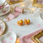 waffle studs in a Decorative setting with teacup, heart-shaped plates, and small pastries on a wooden surface.